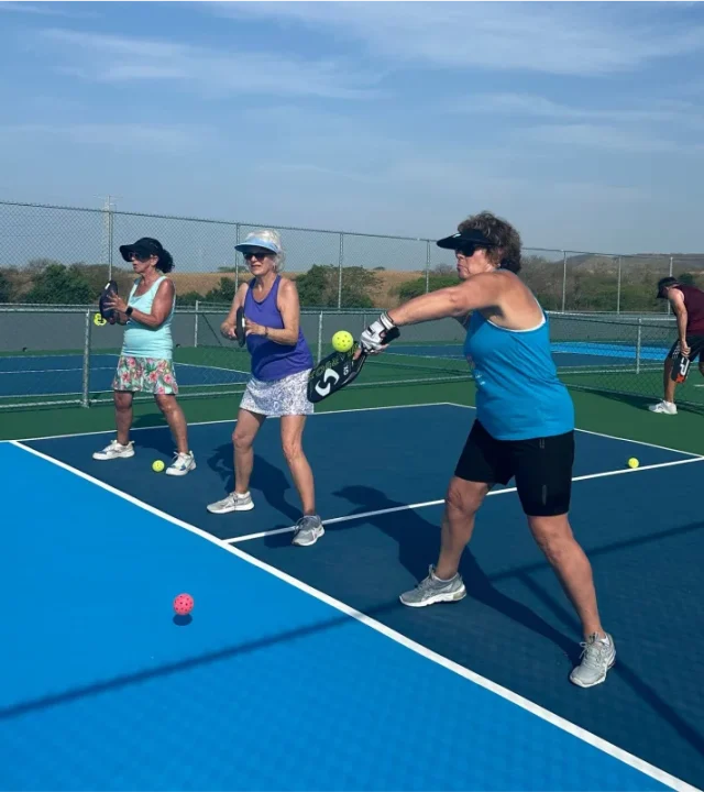 Three women performing pickleball drills at the Pickleball Club courts